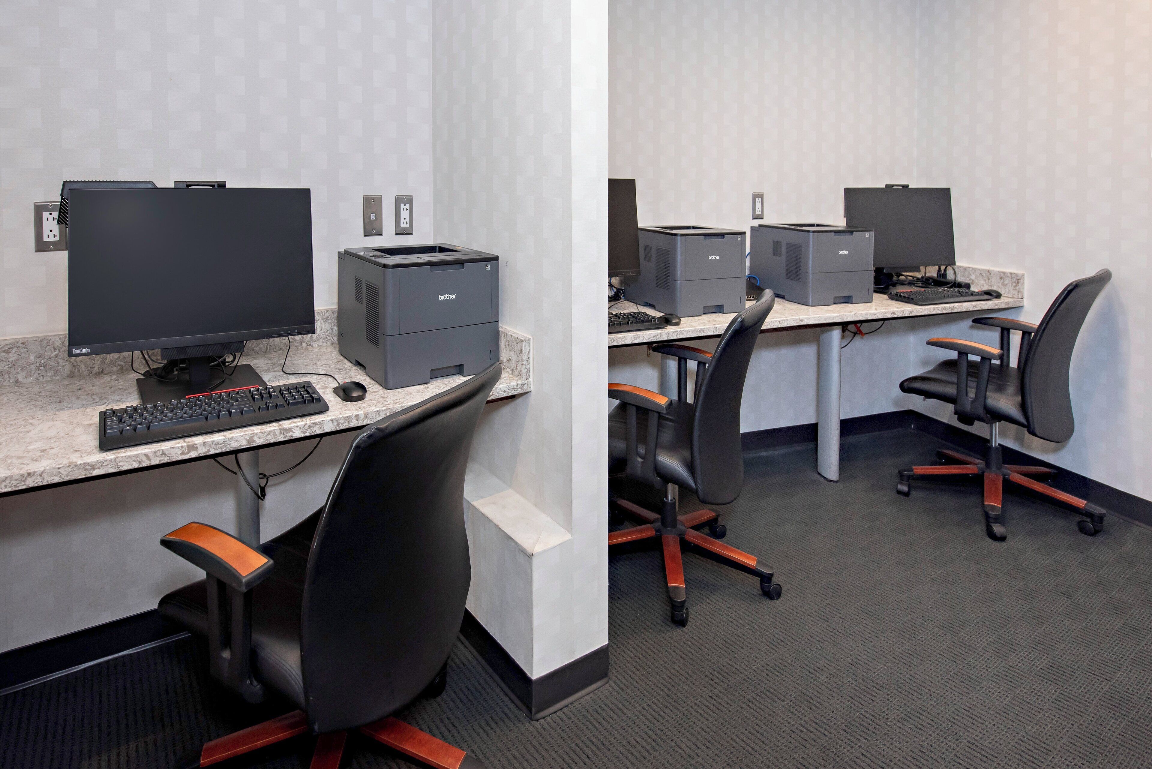 A modern office space with a desktop computer, keyboard, and printer on a marble countertop.