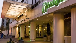 A hotel entrance with a modern facade, large columns, and a prominent illuminated sign. - Holiday Inn Washington Capitol - Natl Mall by IHG (Washington)