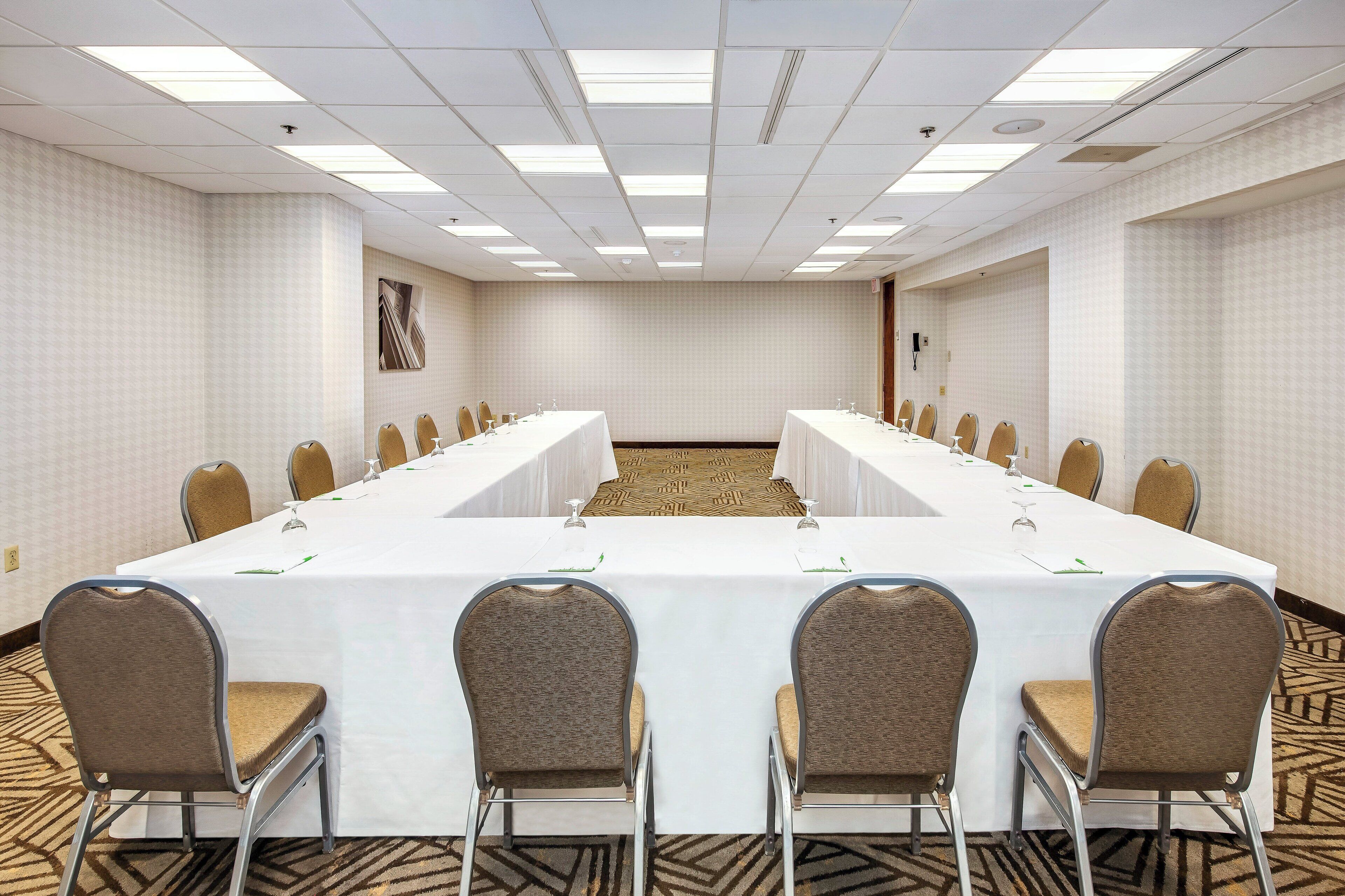 A conference room with a long table, chairs, and a carpeted floor.