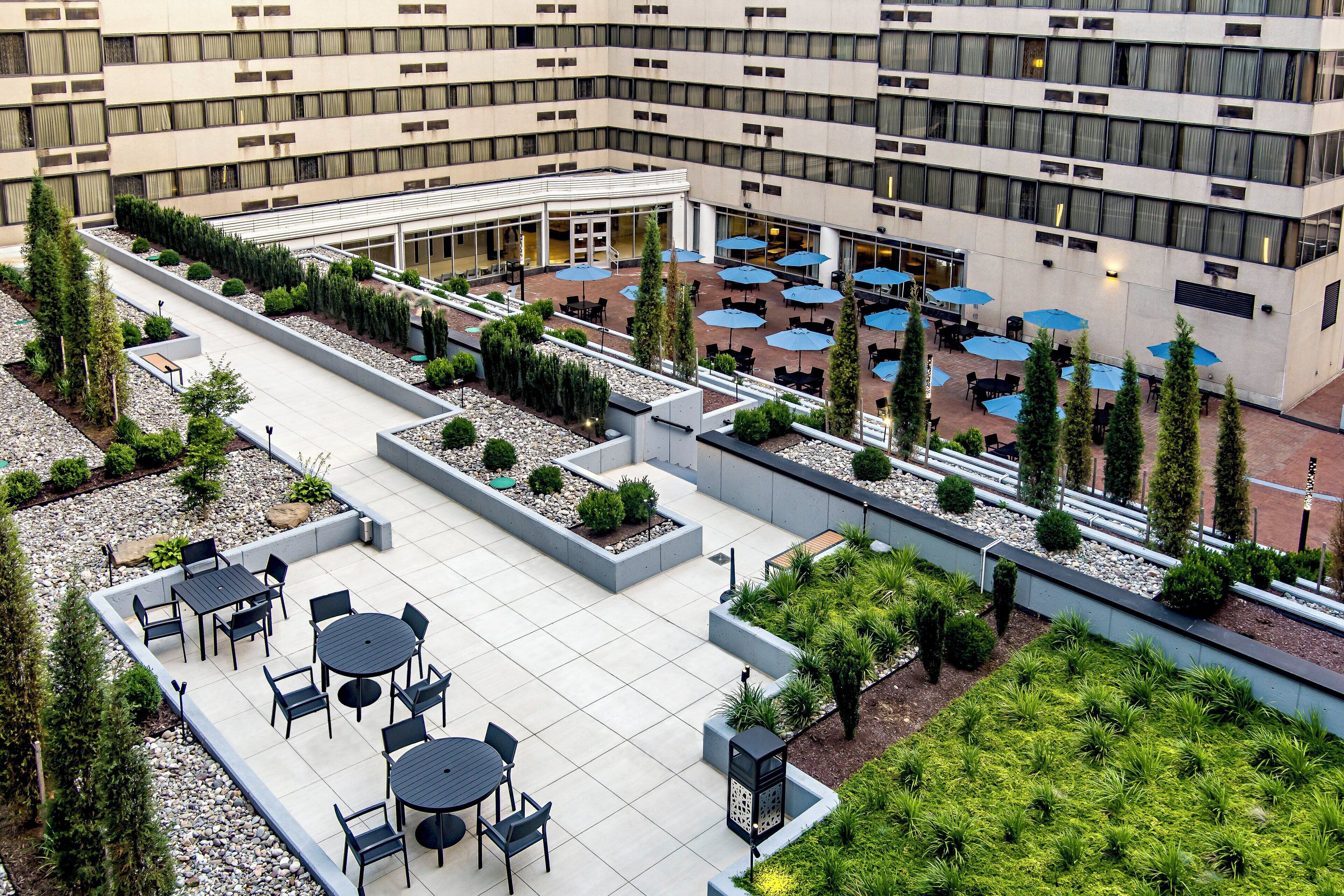 Una terraza en la azotea con mobiliario exterior y un jardín ajardinado.