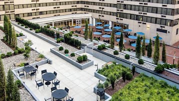 Una terraza en la azotea con mobiliario exterior y un jardín ajardinado.