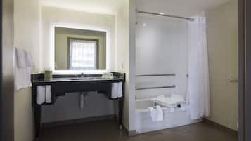 Un baño moderno con un tocador negro, un espejo grande, ducha con puerta de cristal y una bañera.