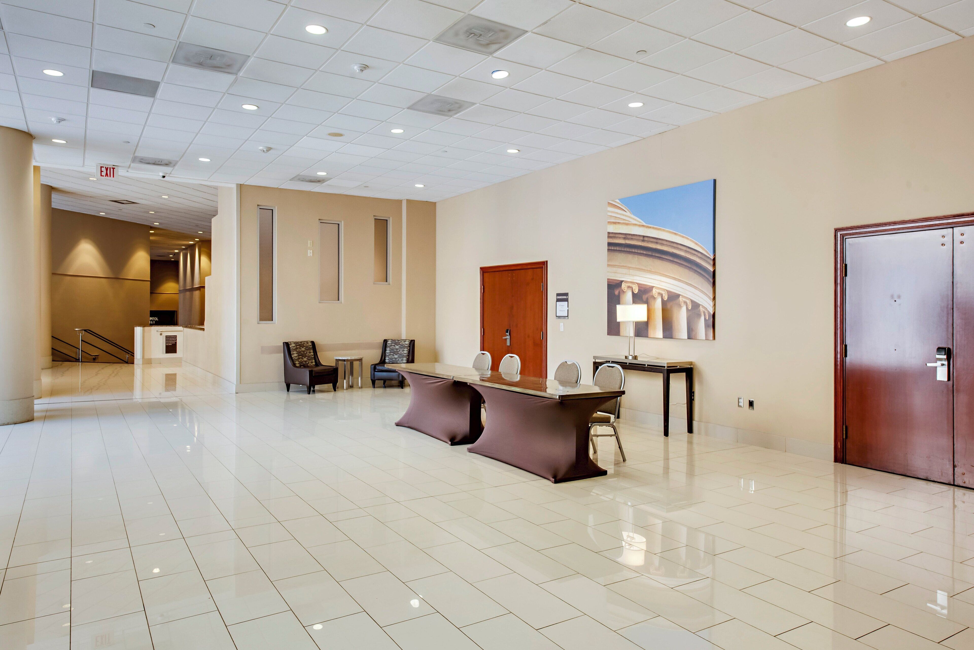 A spacious lobby with a polished tile floor, a reception desk, a seating area, and a large wall mural.