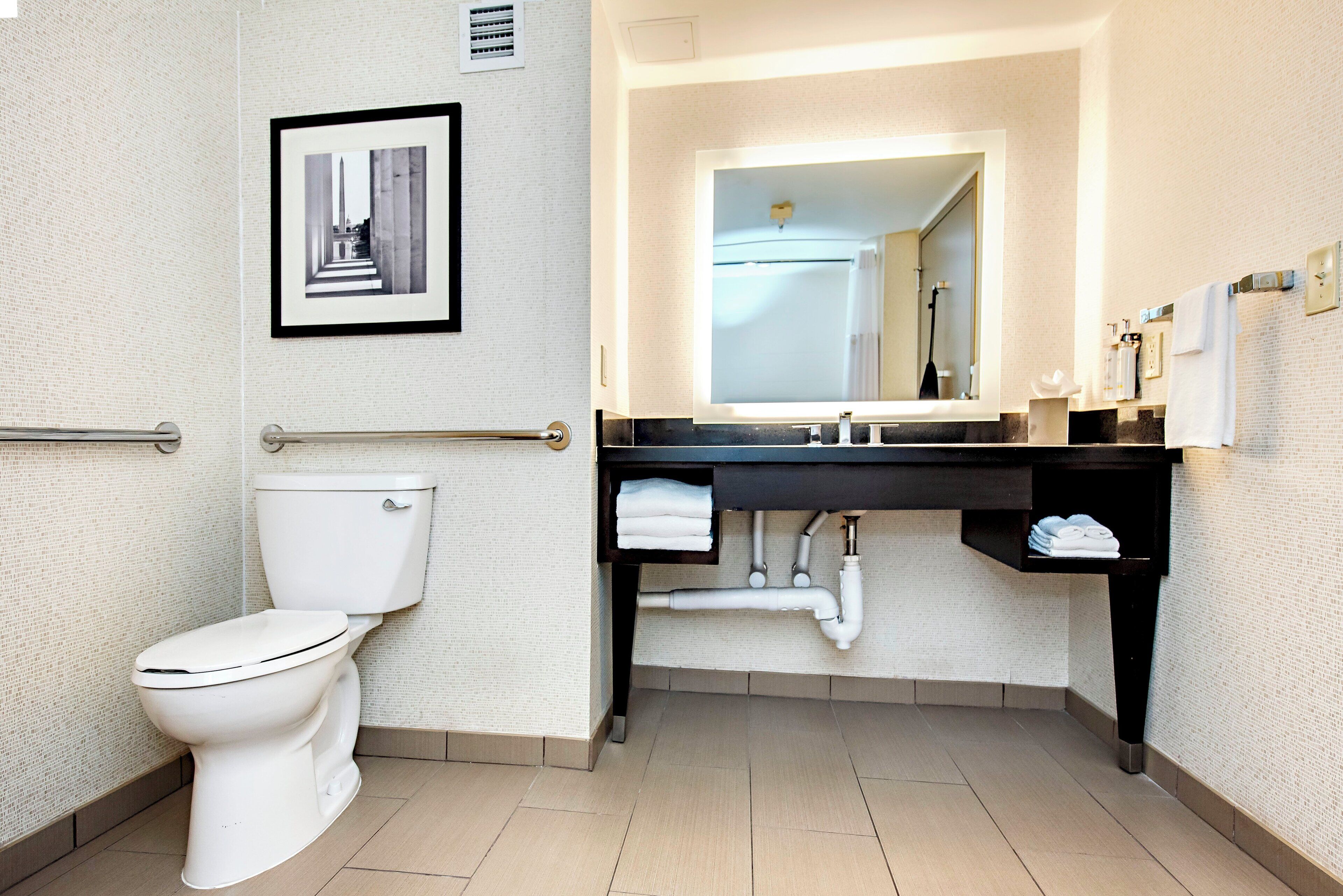 A modern bathroom with a toilet, a sink with a mirror, and a towel rack.
