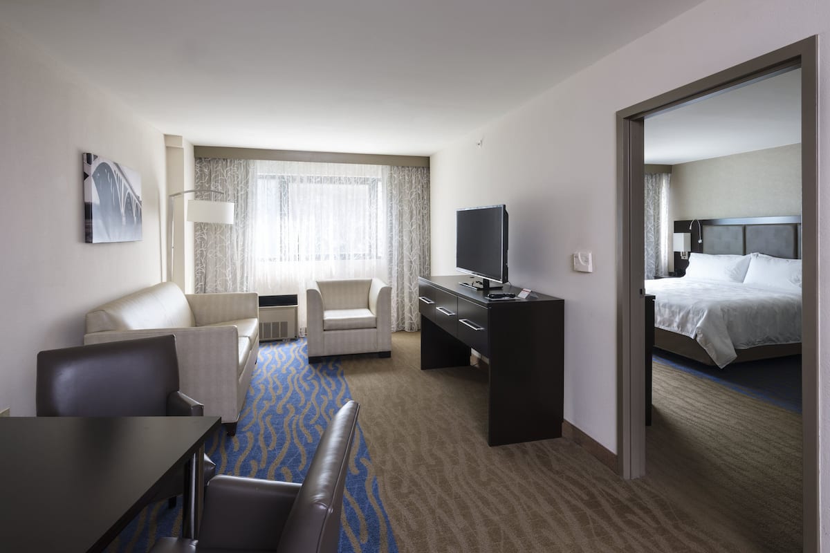 Una habitación de hotel con cama, escritorio, televisor, sofá y una silla.