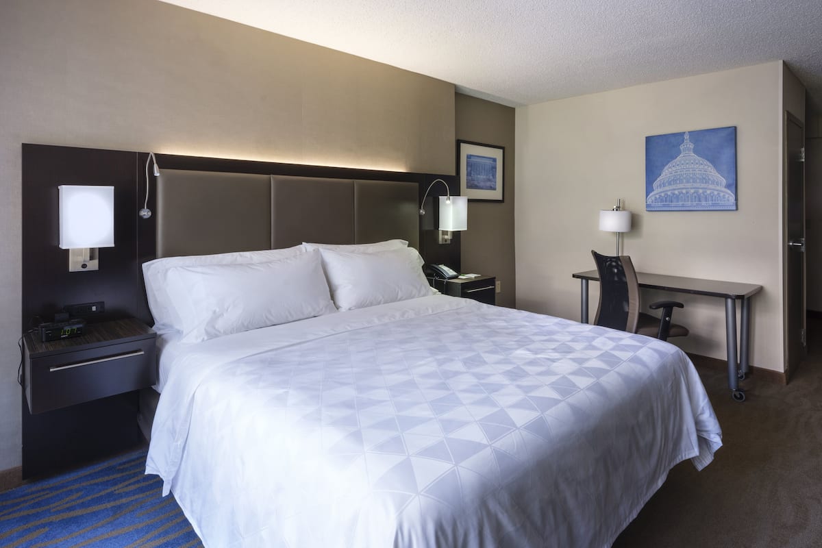 Una habitación de hotel con una cama grande, mesitas de noche, un escritorio y una silla.