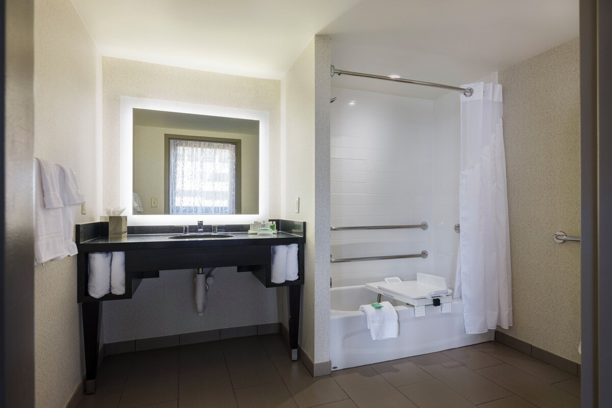 A bathroom with a sink, mirror, towel rack, shower, and bathtub.