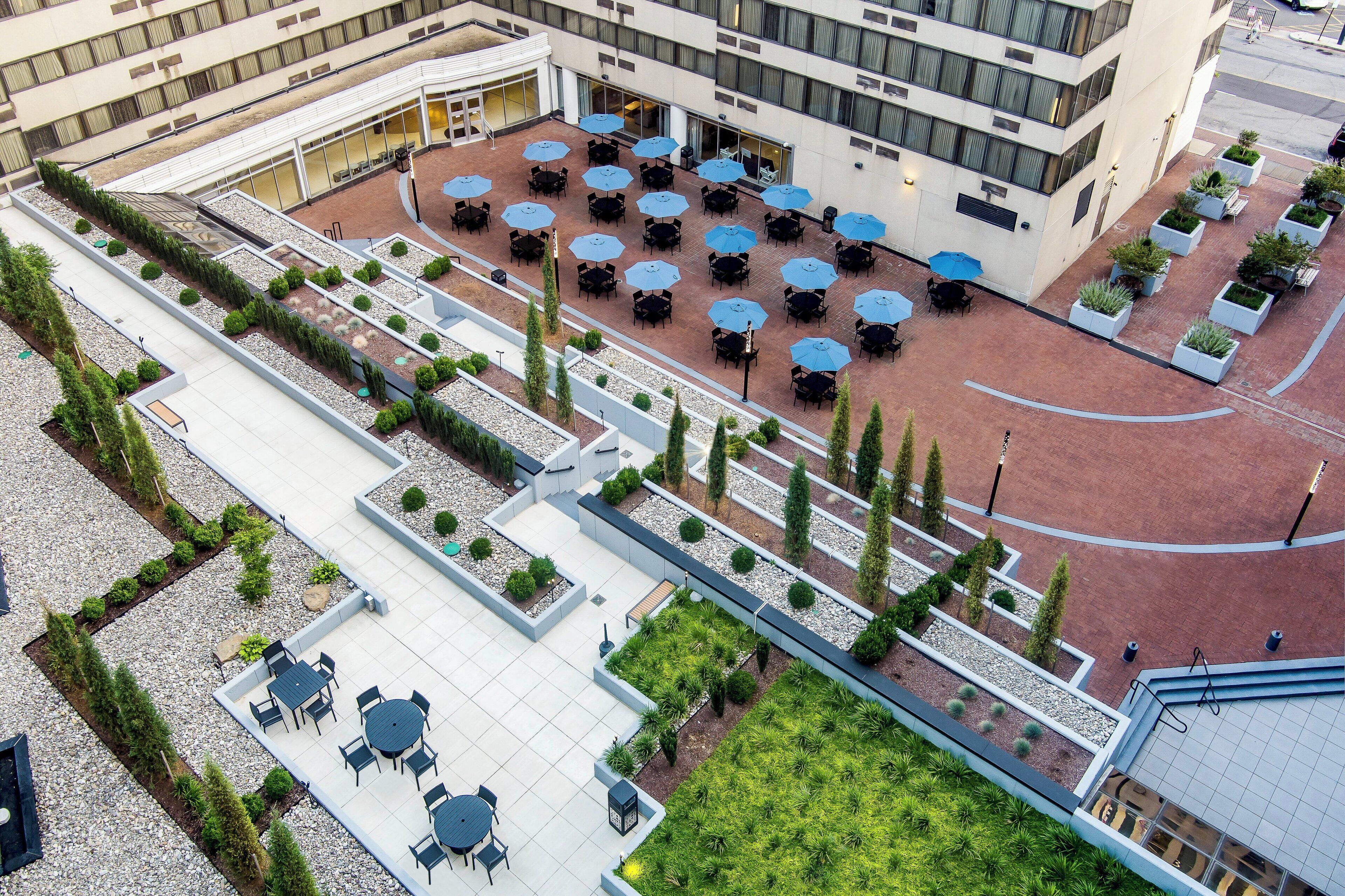 An aerial view of a hotel courtyard with outdoor seating areas, planters, and a central open space.