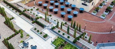 An aerial view of a hotel courtyard with outdoor seating areas, planters, and a central open space.