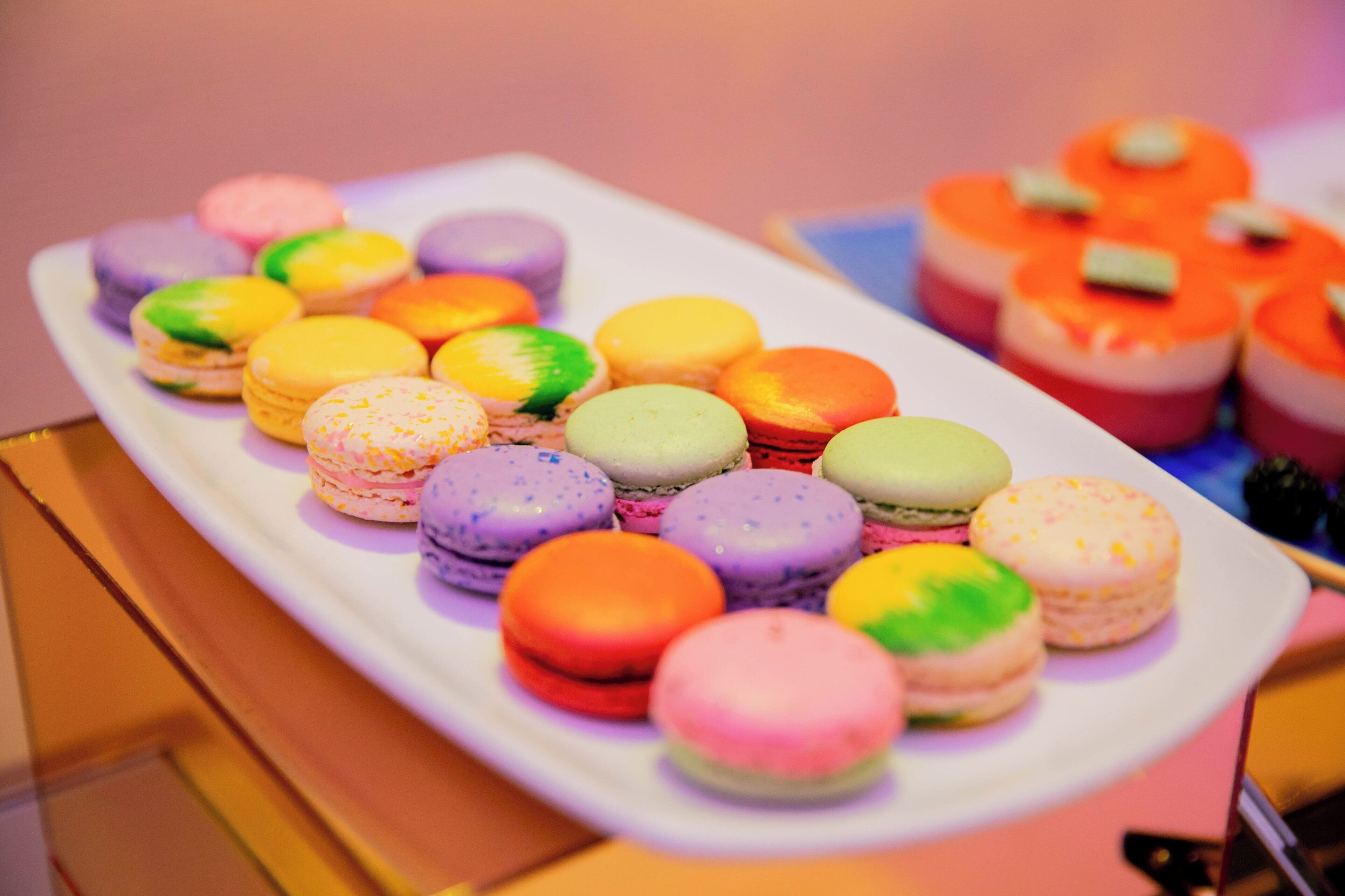 Diversos macarons coloridos dispostos sobre um prato branco.