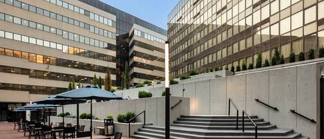 A modern building with a courtyard featuring outdoor seating and a staircase.