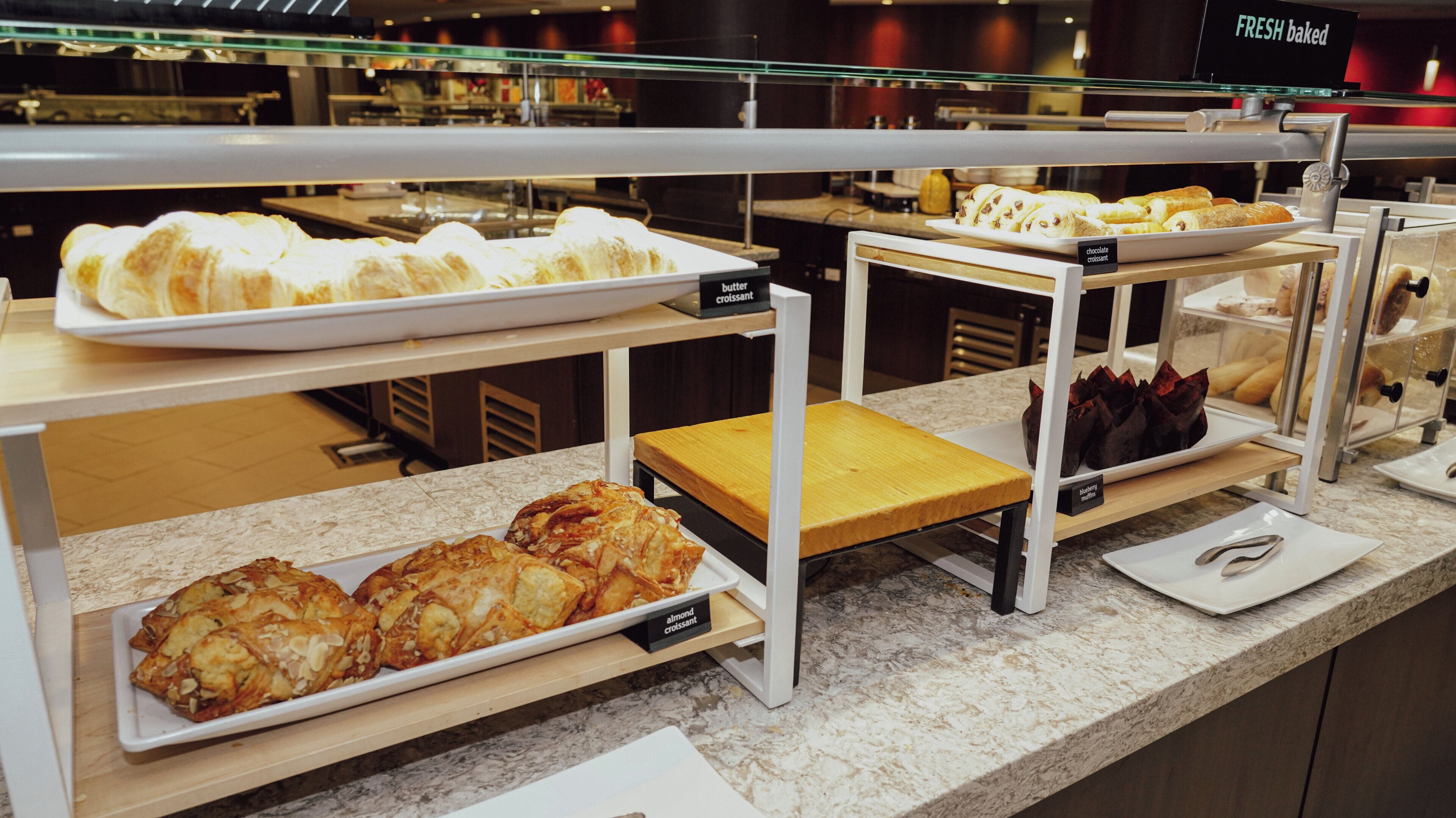 A bakery display with various pastries and bread, including croissants and muffins.