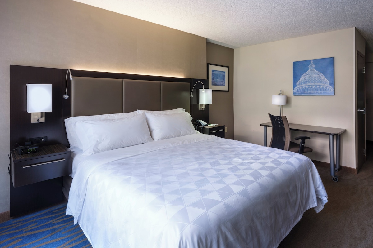 A hotel room with a large bed, bedside tables, a desk, and a chair.