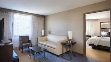 Habitación de hotel con cama, sofá, escritorio, silla, televisor y lámpara.