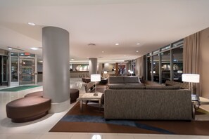 A modern lobby with a seating area, a reception desk, and a glass entrance.