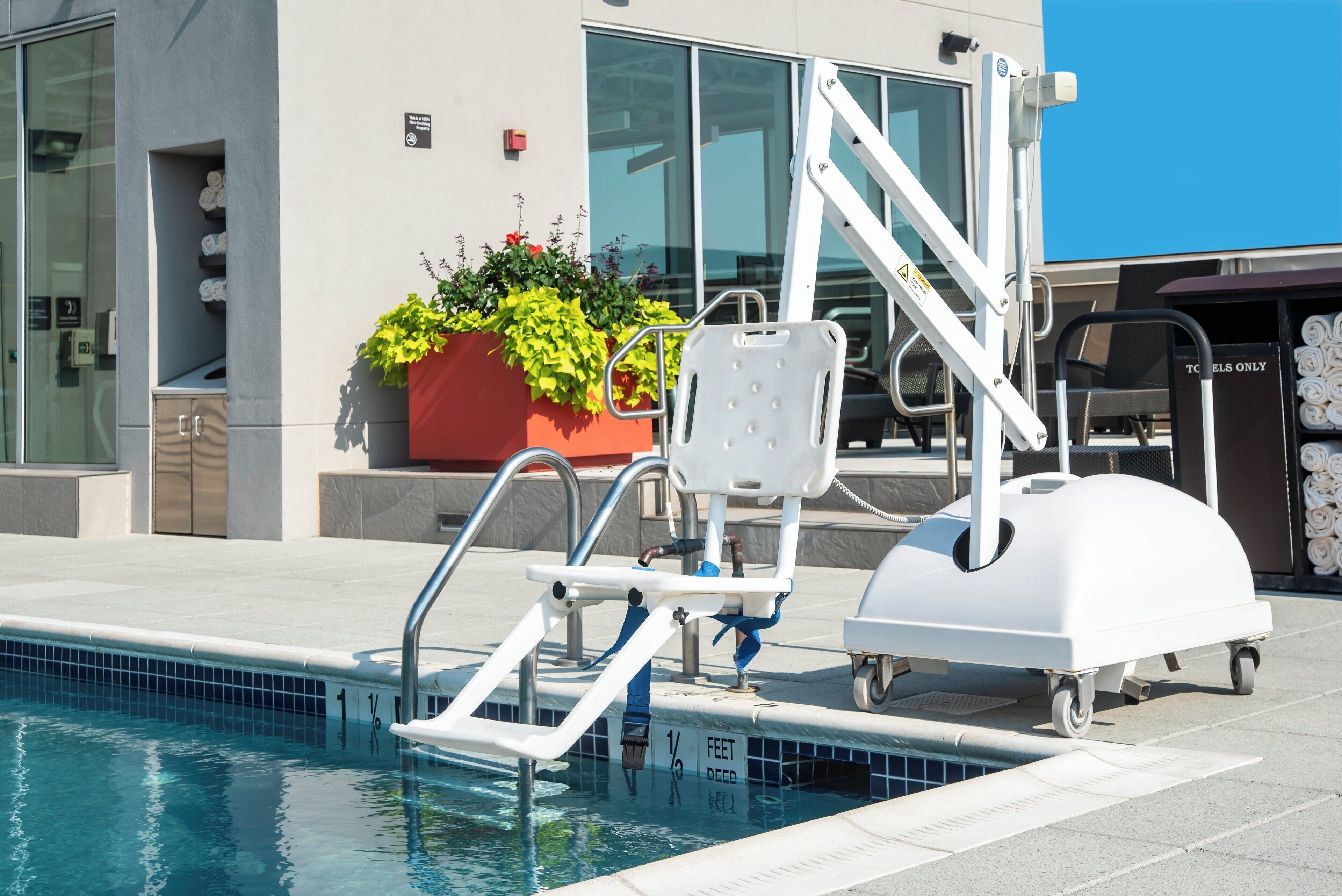 Zona de piscina con elevador para piscina, escalera de piscina y tobogán acuático.