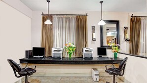 A reception area with two black office chairs, a black desk with two monitors, a printer, and a vase of flowers. - Ramada by Wyndham West Memphis (West Memphis)