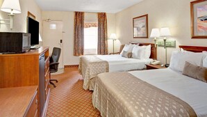 A hotel room with two beds, a desk with a television, a chair, a desk lamp, and a telephone. - Ramada by Wyndham West Memphis (West Memphis)