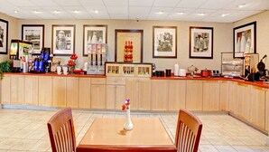 A restaurant with a wooden counter, framed pictures on the wall, and a vase with flowers on the table. - Ramada by Wyndham West Memphis (West Memphis)
