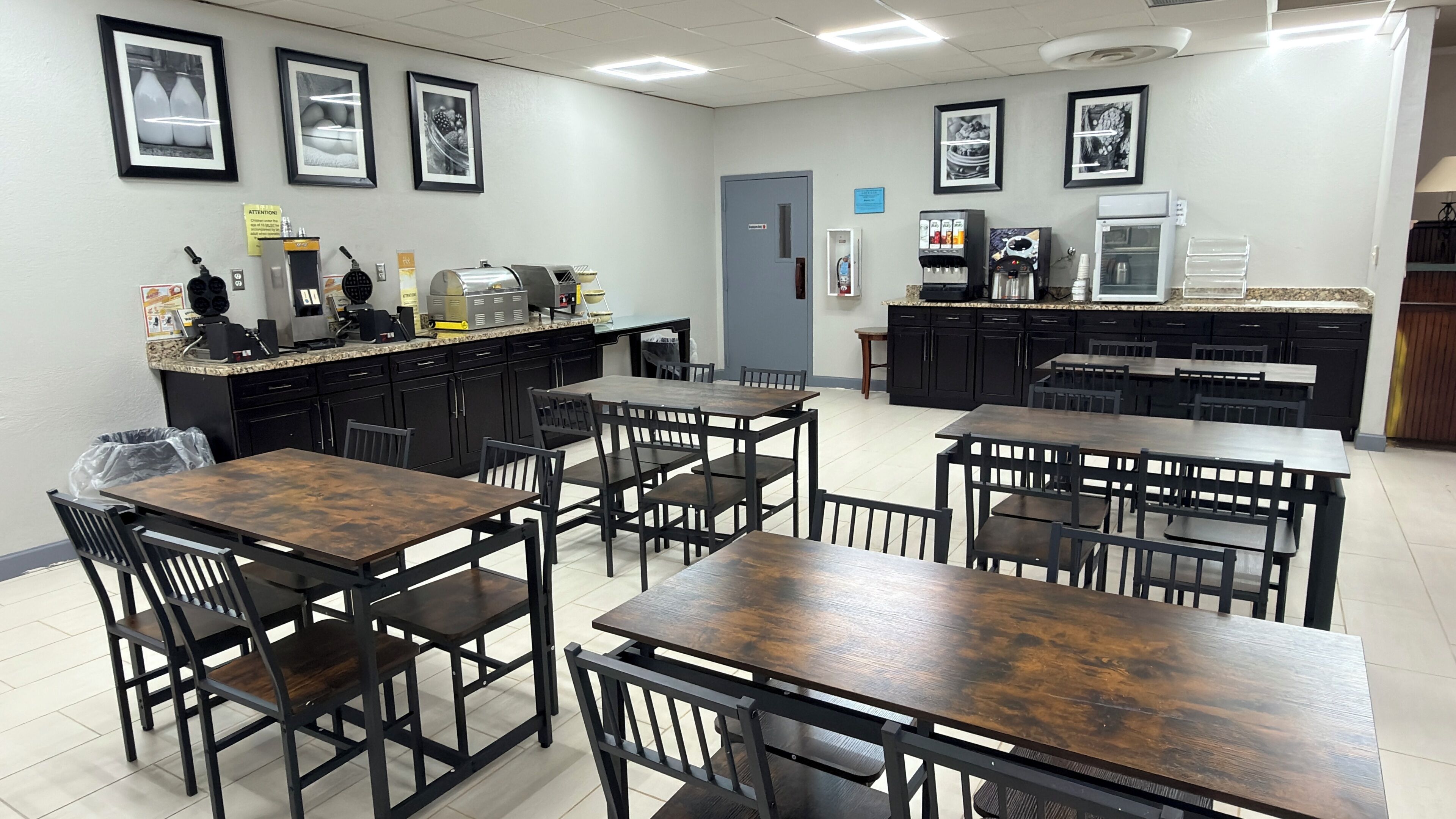 A dining area with tables and chairs, a coffee machine, and a refrigerator.
