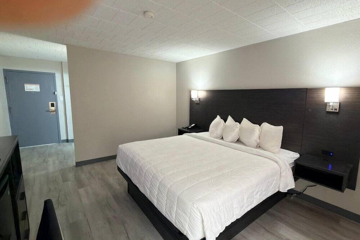 A hotel room with a large bed, a desk, and a chair.