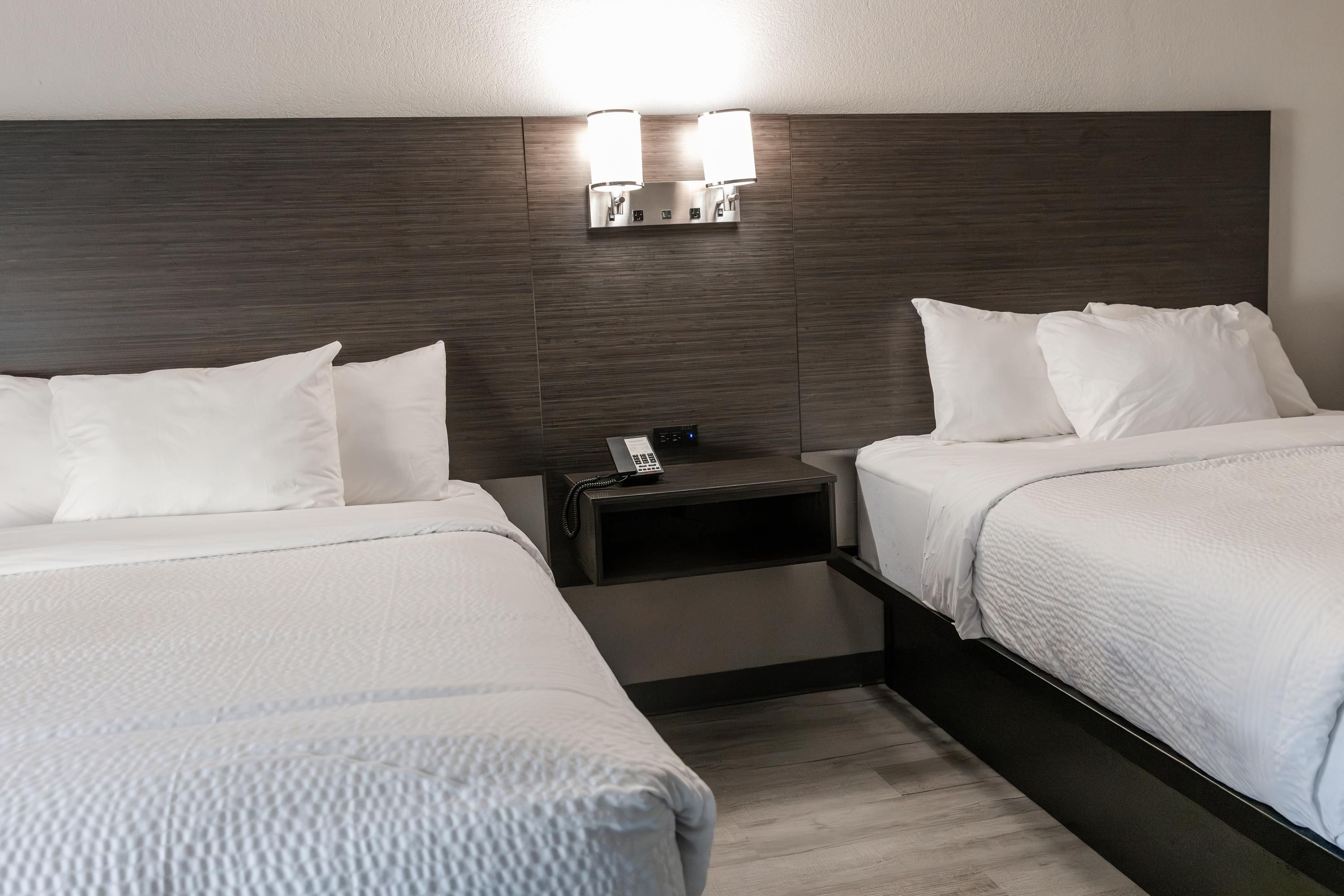 Ein Hotelzimmer mit zwei Betten, einem Nachttisch mit Telefon und Wandleuchten.