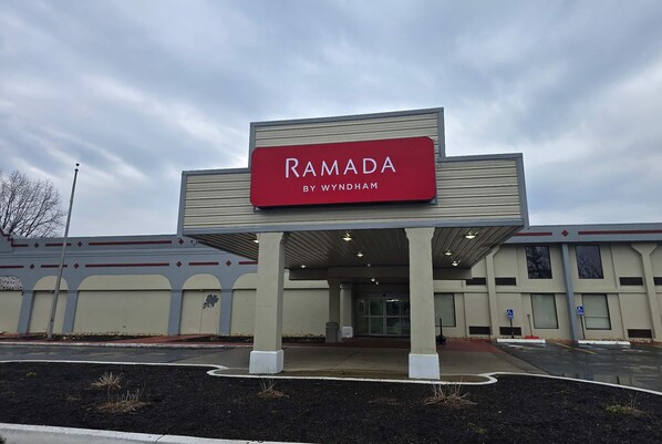 Un bâtiment sur lequel on peut lire l’inscription « RAMADA BY WYNDHAM » et qui possède une entrée abritée.