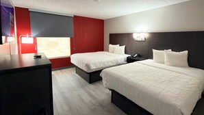 Hotellihuone, jossa on kaksi sänkyä, työpöytä, punainen tehosteseinä ja ikkuna.