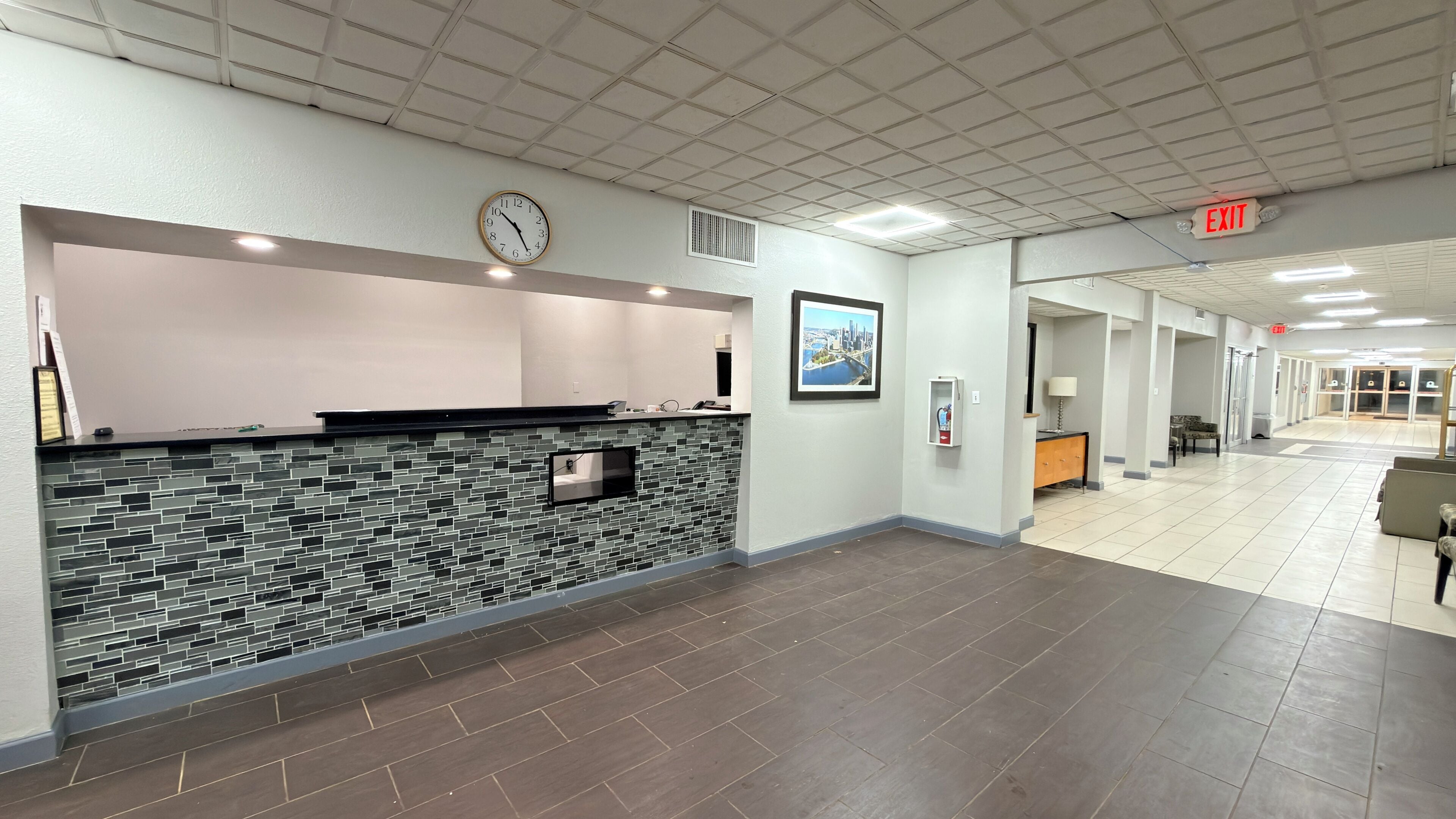 A reception area with a clock, a fire extinguisher, and an exit sign.