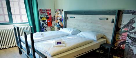 A double bed with a wooden frame, a small bedside table, and a poster on the wall.