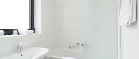 Un baño con un lavamanos blanco, una bañera y un ventanal.