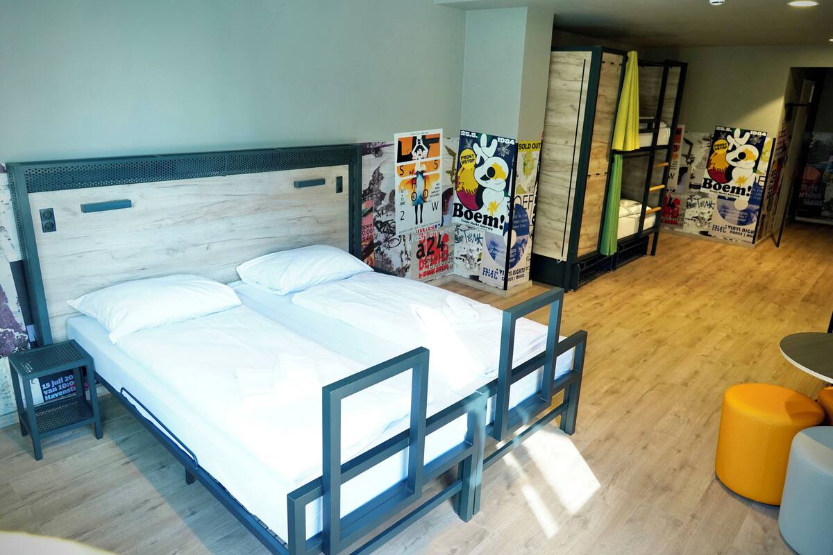 A hotel room with a bed, a small table, and a sofa.