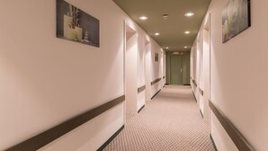 A corridor with white walls, a patterned carpet, and framed artwork on the walls. - a&o Antwerpen Centraal (Antwerp)