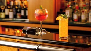 Un bar avec deux cocktails sur le comptoir, un distributeur de Pepsi et, en arrière-plan, une variété de bouteilles.
