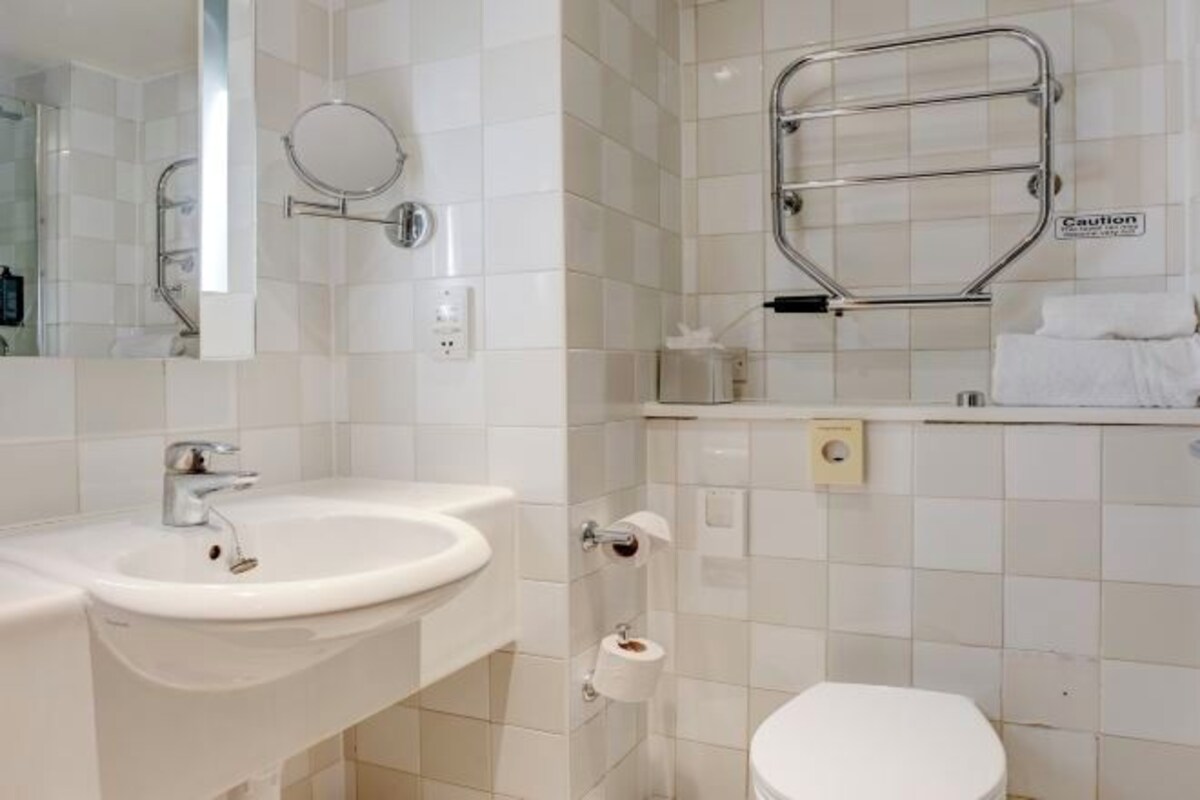 A bathroom with a white sink, toilet, and a towel rack.