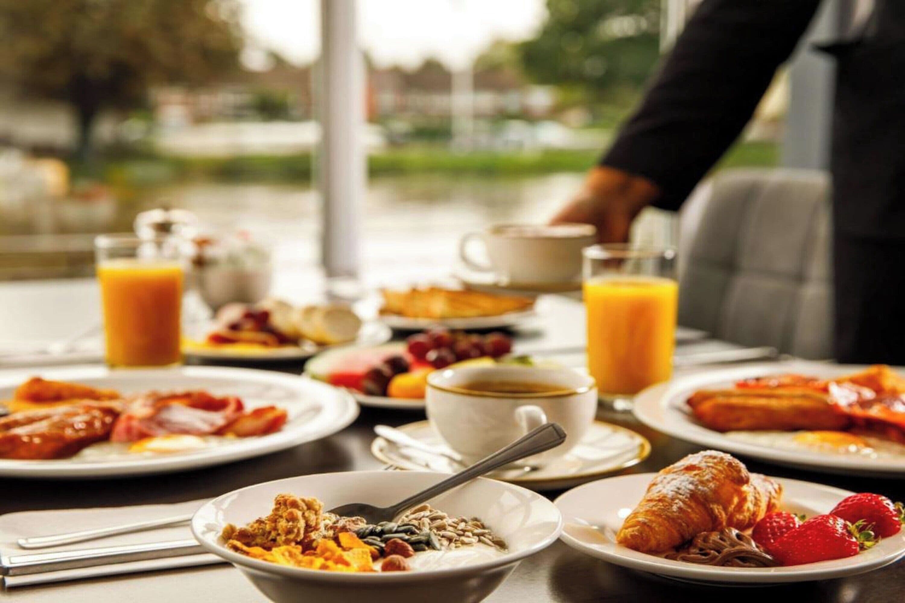 A breakfast table with plates of food, a croissant, and a cup of coffee.