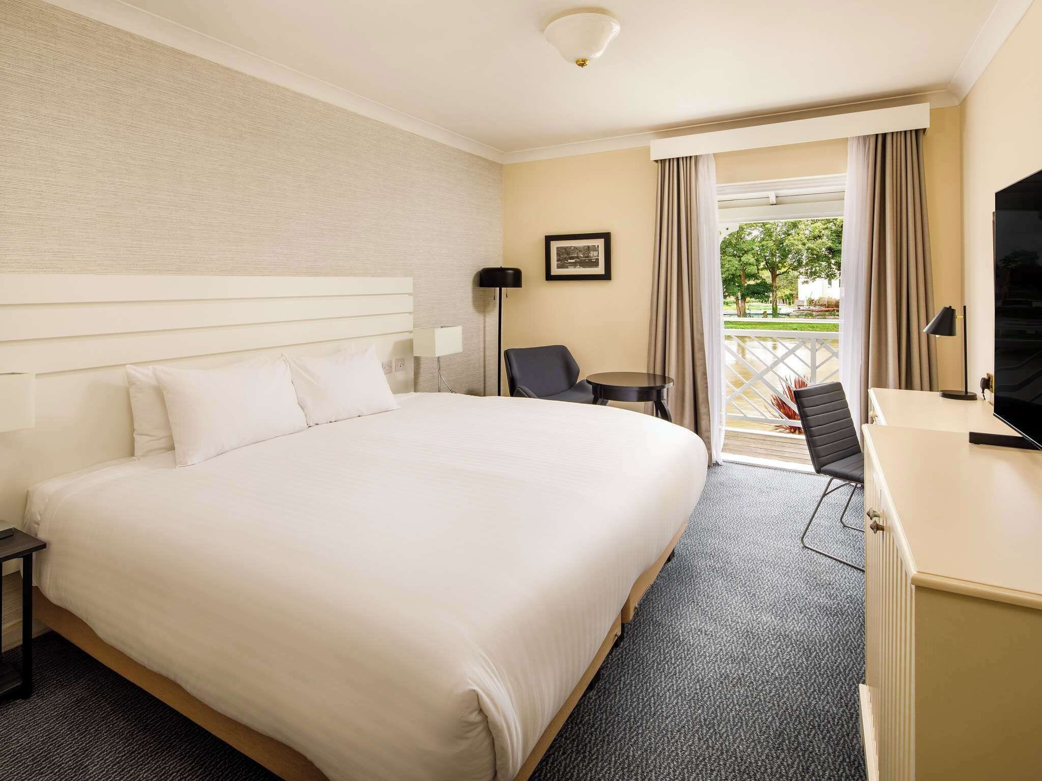 Une chambre d’hôtel avec un grand lit, un bureau, une chaise, une télévision et une vue sur l’extérieur.