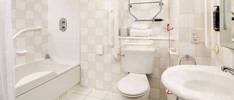 A bathroom with a bathtub, toilet, and sink, featuring a tiled floor and walls.