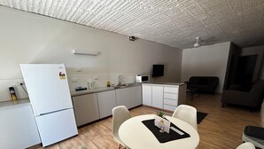 Une cuisine compacte équipée d’un réfrigérateur, d’un four à micro-ondes et d’un évier. Un coin repas avec une table et des chaises est également disponible.