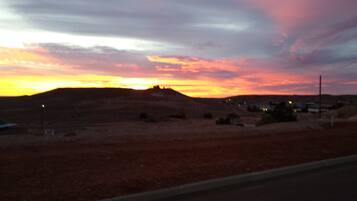 A sunset over a barren landscape with a road in the foreground.