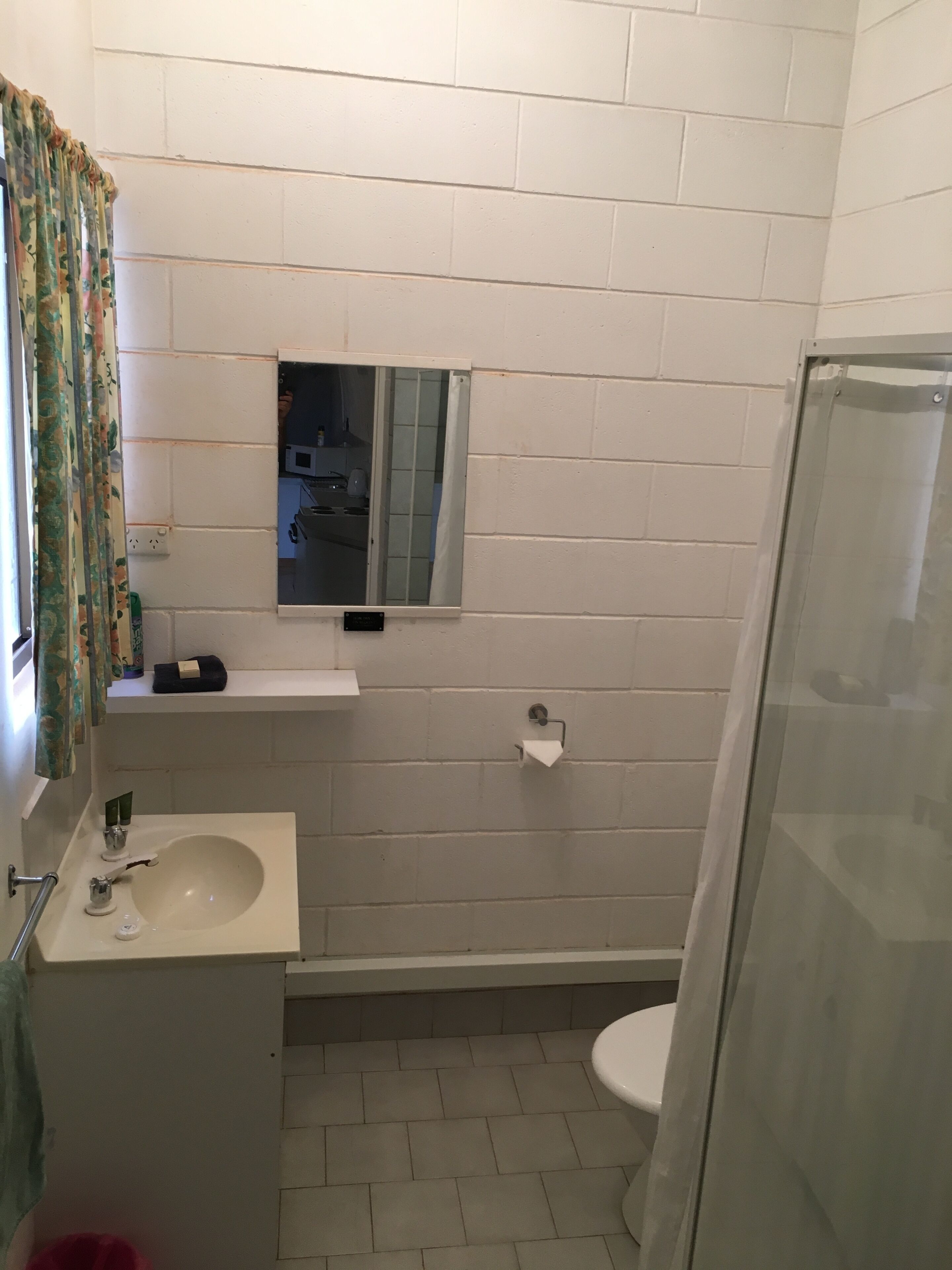 A bathroom with a sink, mirror, toilet, and shower.