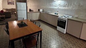 Une cuisine de taille réduite avec une table à manger en bois, des placards blancs, une cuisinière et un four à micro-ondes.