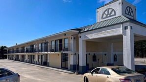 Un motel con una torre central, varios balcones y un estacionamiento.