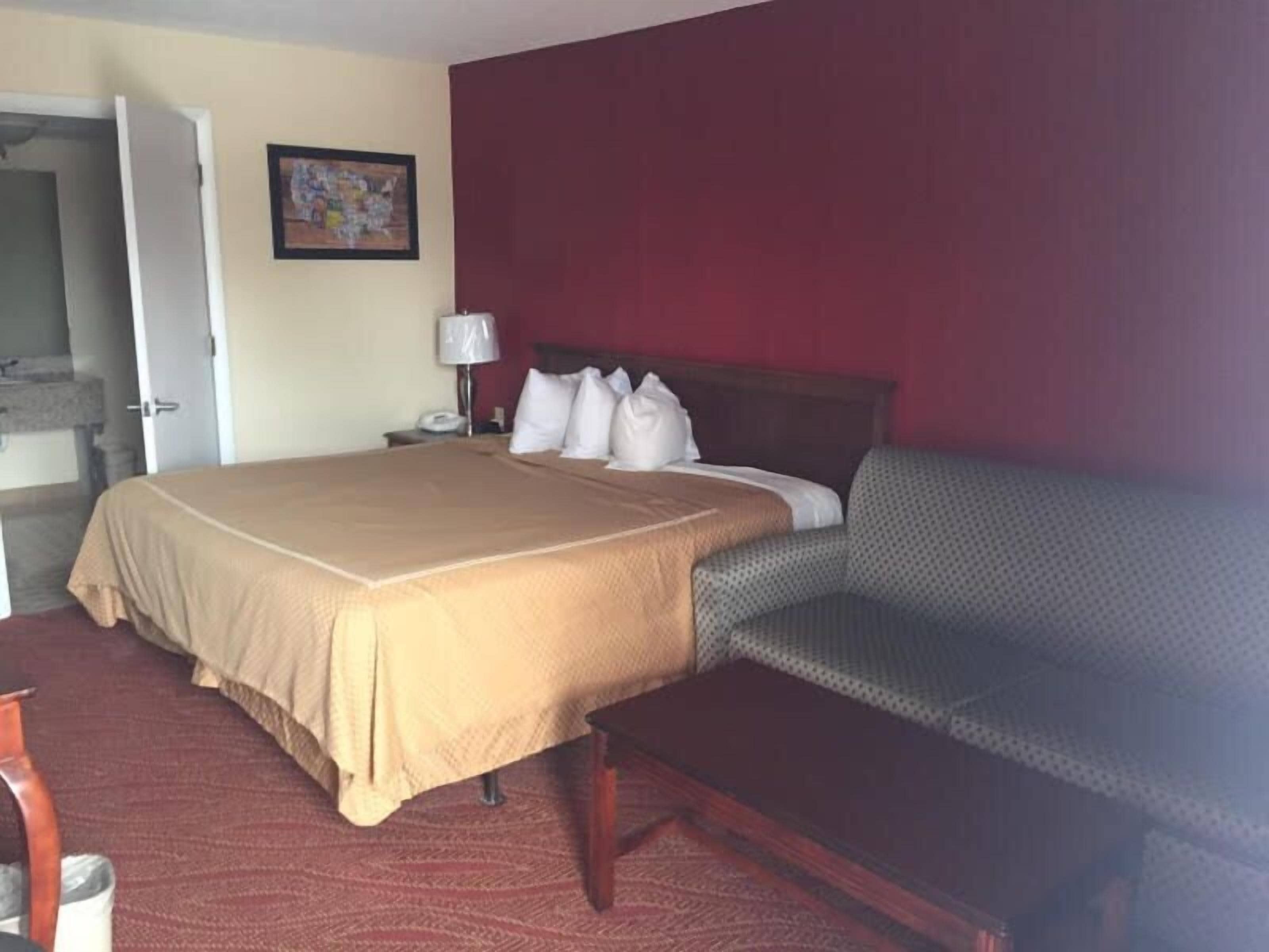 A hotel room with a bed, a nightstand, a lamp, and a chair.