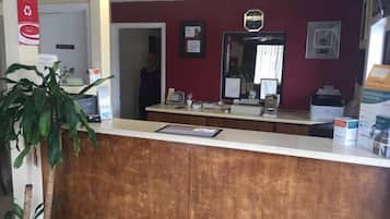 A reception area with a wooden counter, a large mirror, and a potted plant.