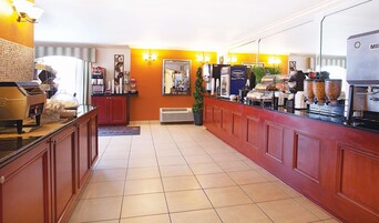 A hotel lobby with a long reception desk, a coffee machine, and a buffet area.
