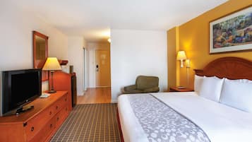 A hotel room with a bed, television, dresser, and lamps.