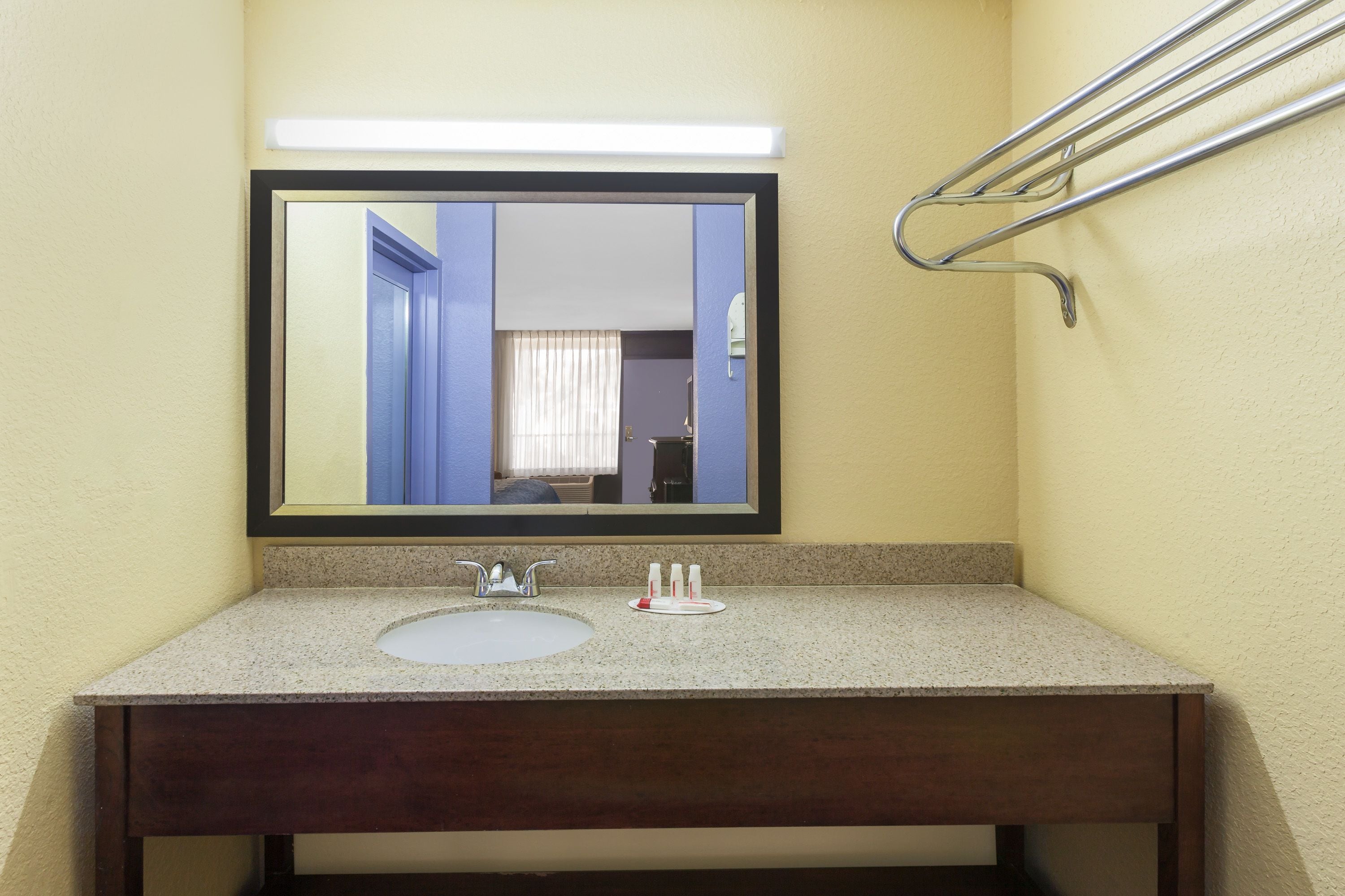 A bathroom with a sink, mirror, and towel rack.