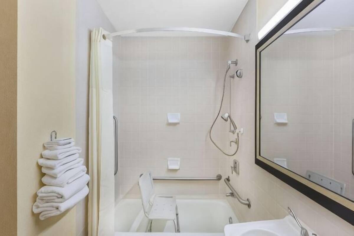 A bathroom with a bathtub, a shower, a sink, and a mirror.