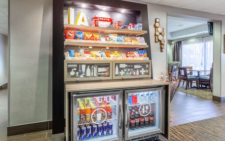 A hotel lobby with a snack display, a seating area, and two beverage refrigerators.